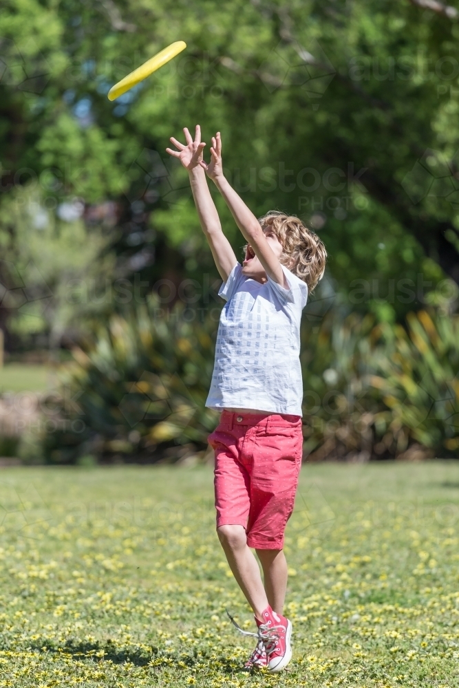 A young boy reaching to catch a frisbee - Australian Stock Image