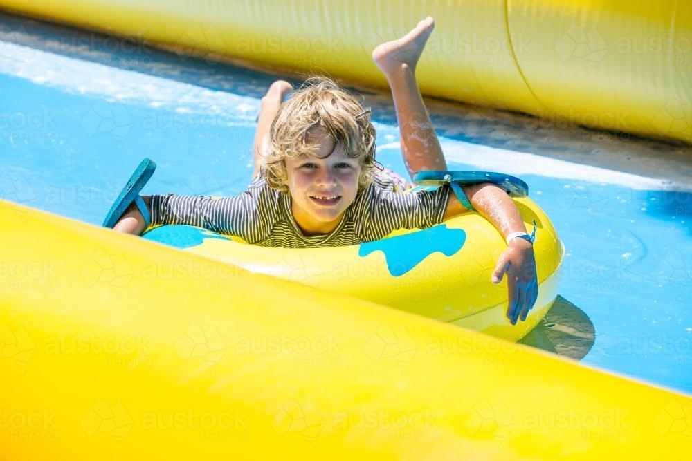 A young boy rides a waterslide - Australian Stock Image