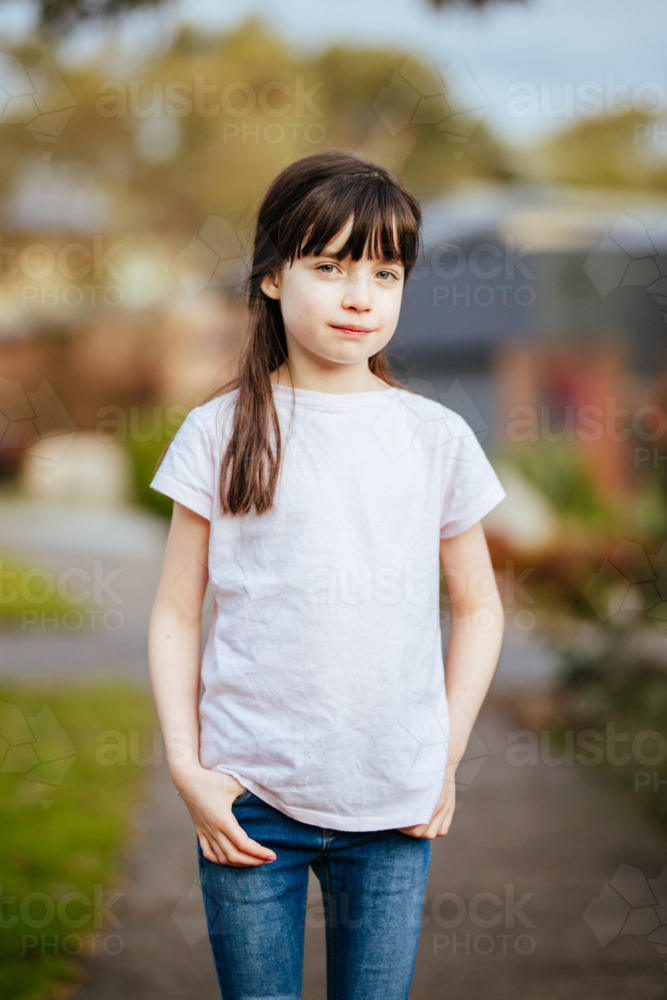 A young caucasian girl poses in the street with plain clothing on a sunny evening in Australia - Australian Stock Image