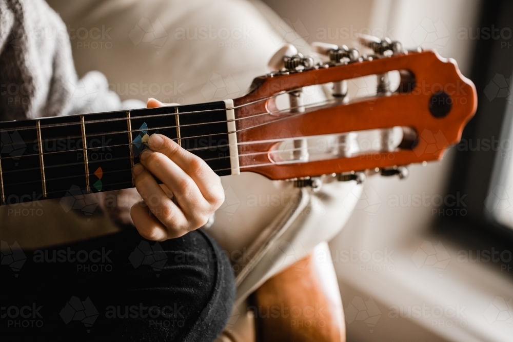 A young caucasion girl practicing playing her guitar - Australian Stock Image