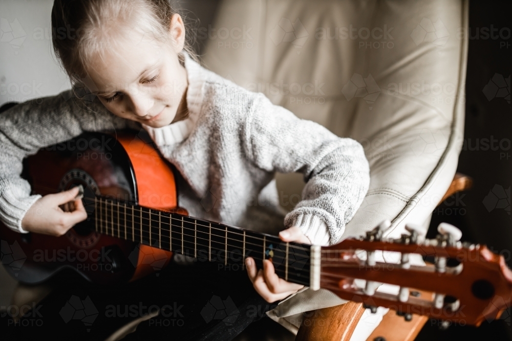 A young caucasion girl practicing playing her guitar - Australian Stock Image