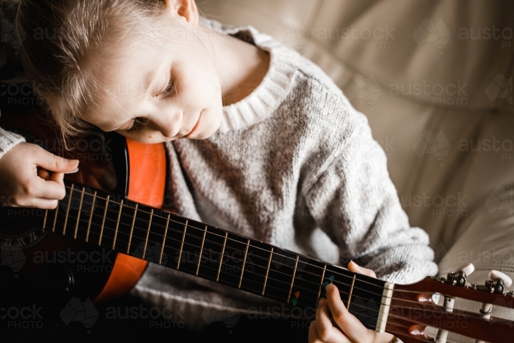A young caucasion girl practicing playing her guitar - Australian Stock Image