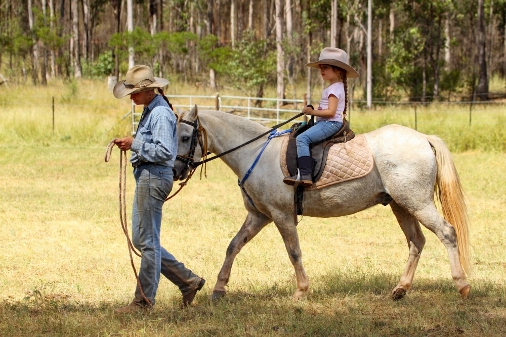 A young country girl being led on a pony by mum. - Australian Stock Image