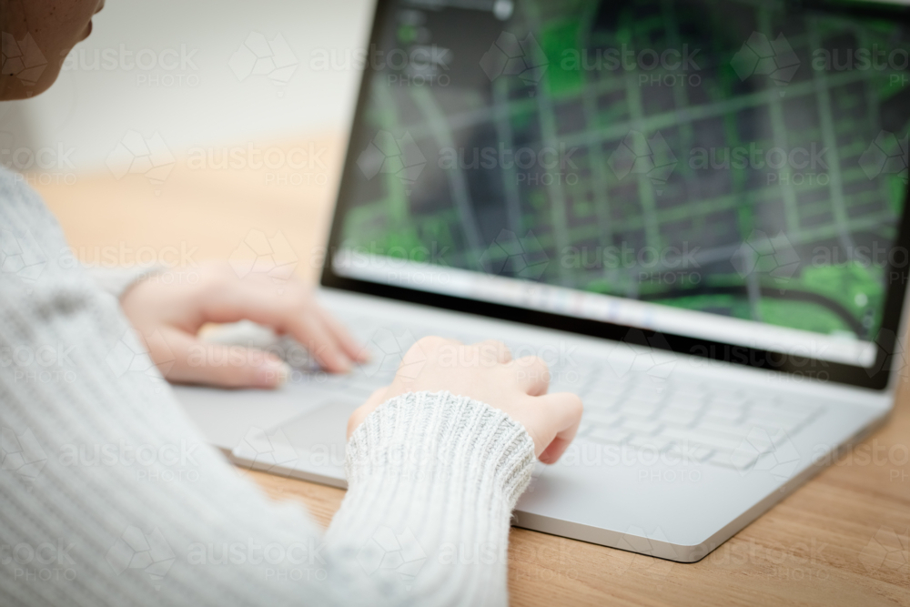 A young female child uses a computer in remote learning for her school work - Australian Stock Image