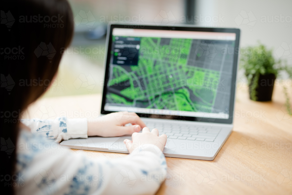 A young female child uses a computer in remote learning for her school work - Australian Stock Image