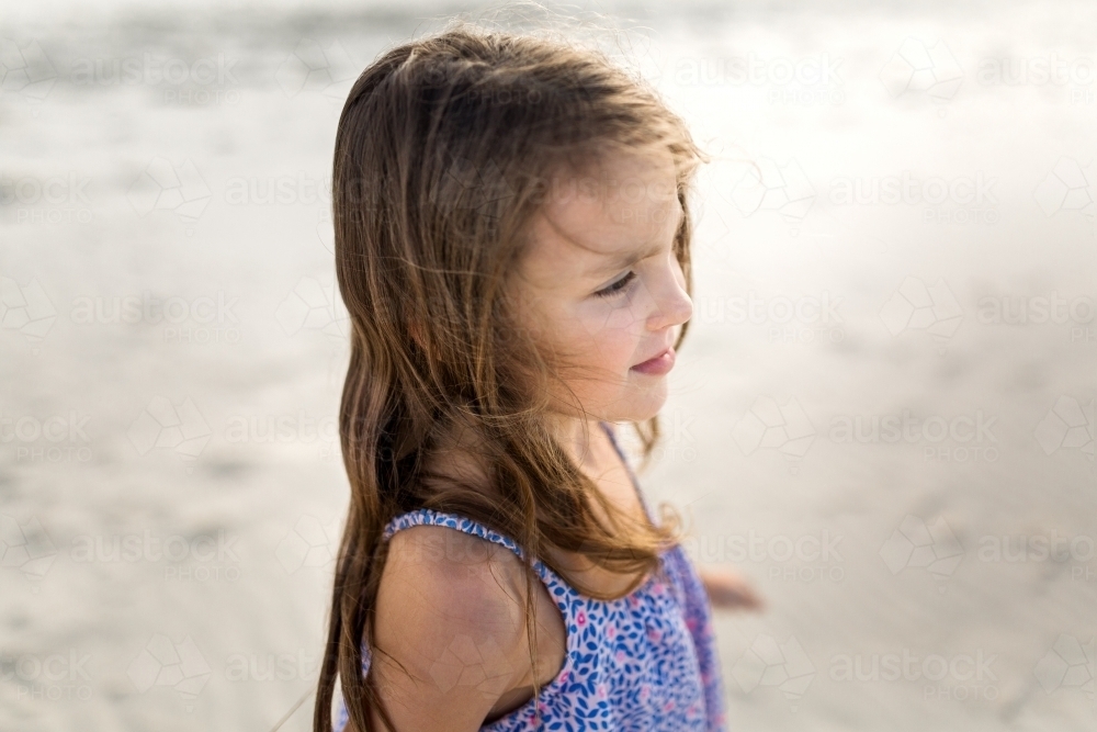 A young girl at the beach watching the ocean - Australian Stock Image