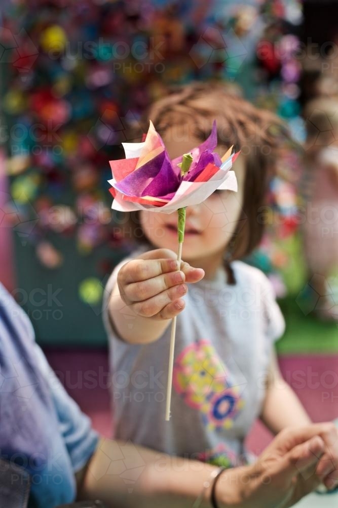 A young girl / child holds up a paper flower she has made - Australian Stock Image