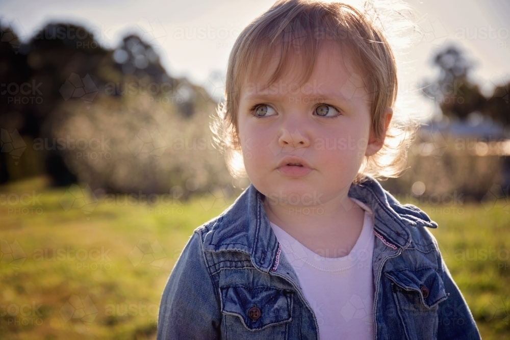 A Young Girl Looking Away From the Camera With Her Hair Backlit - Australian Stock Image
