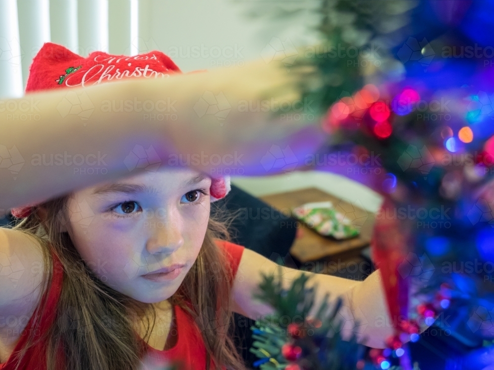 A young girl of mixed race decorating a Christmas tree - Australian Stock Image