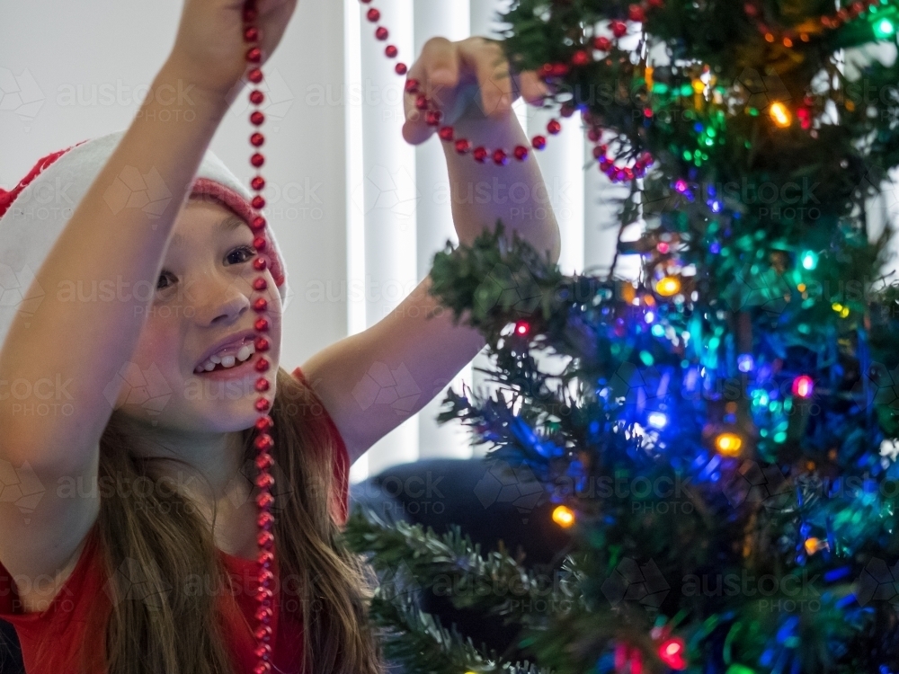 A young girl of mixed race decorating a Christmas tree - Australian Stock Image
