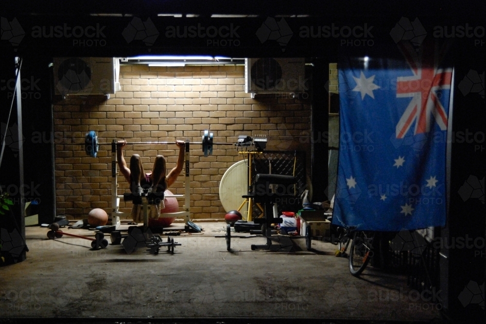 A young man doing weights at night near an Australian flag - Australian Stock Image