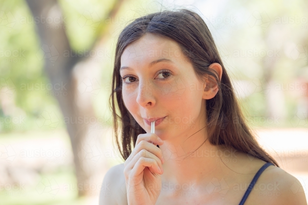 Image of A young woman eating off a plastic spoon Austockphoto
