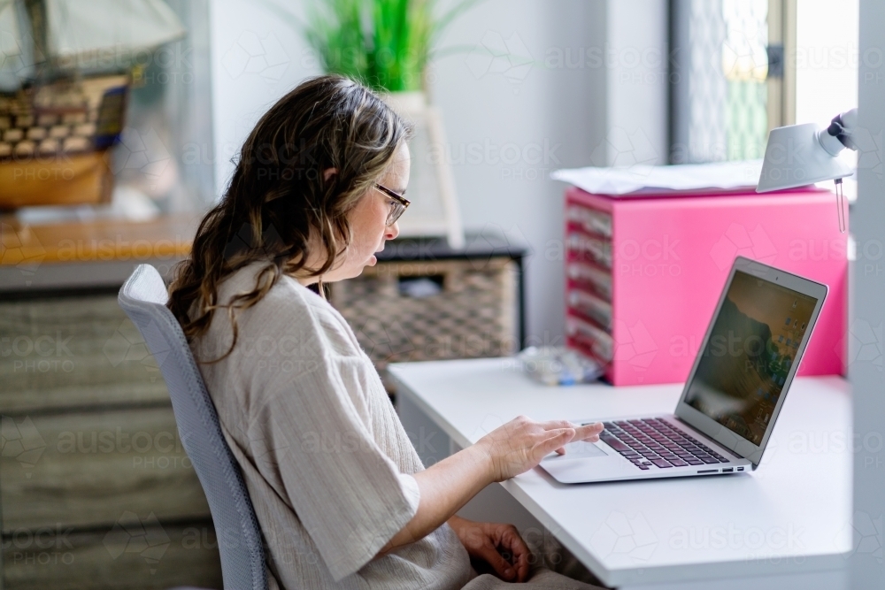 a young woman with Down Syndrome uses a computer at home. - Australian Stock Image