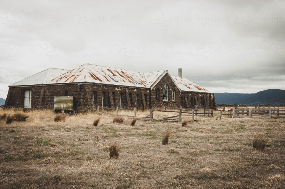 abandoned bluestone shearing shed in the dry grassy landscape - Australian Stock Image
