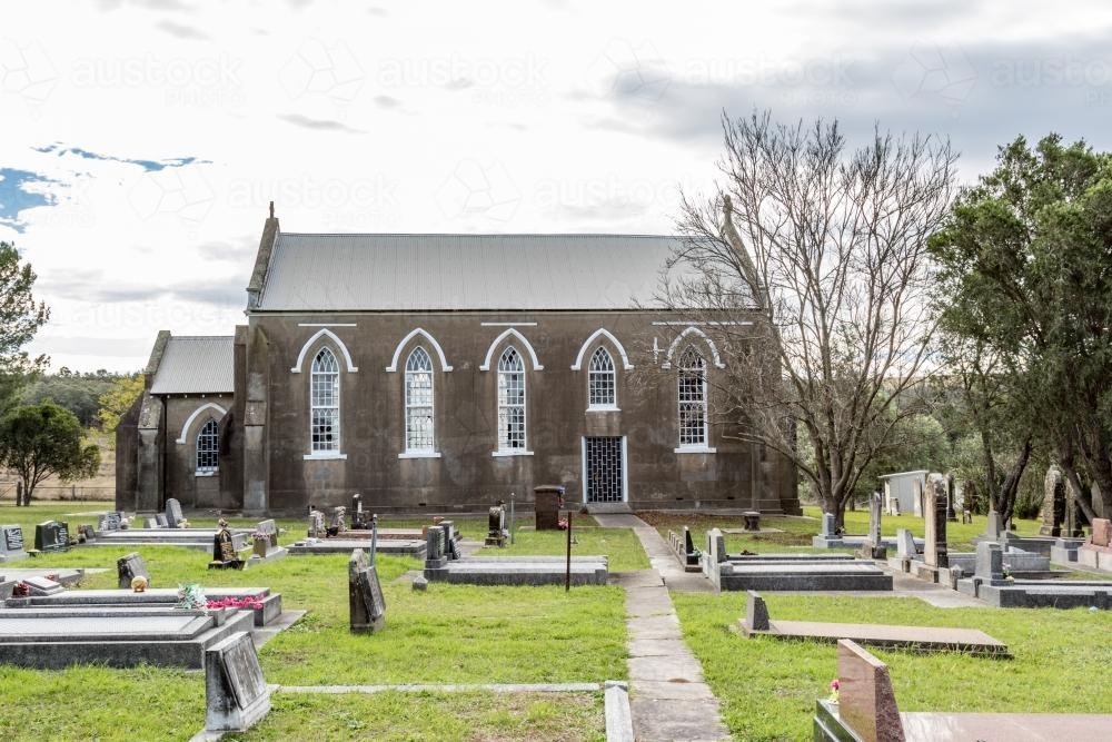 Abandoned grey stone country church and graveyard - Australian Stock Image
