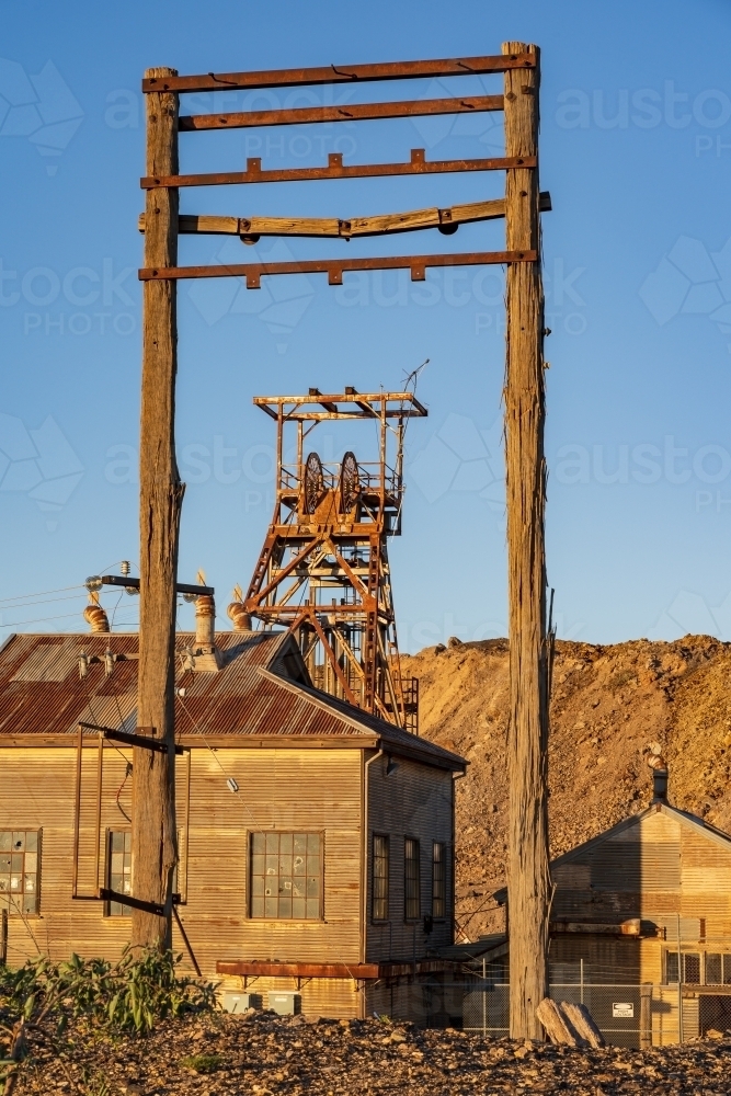 Abandoned mining structures and poppet head tower with late afternoon lighting - Australian Stock Image