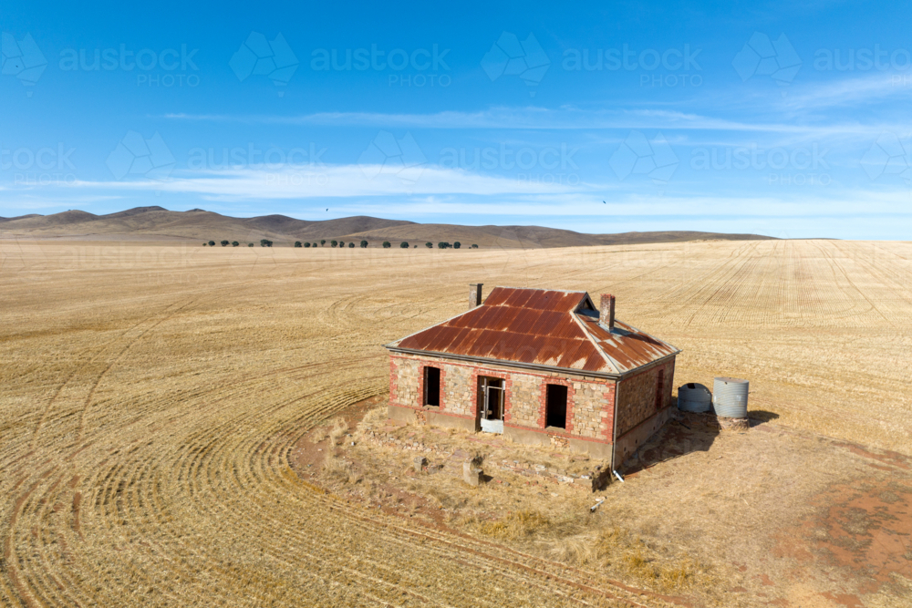 Abandoned stone farmhouse in a vast harvested wheat field - Australian Stock Image