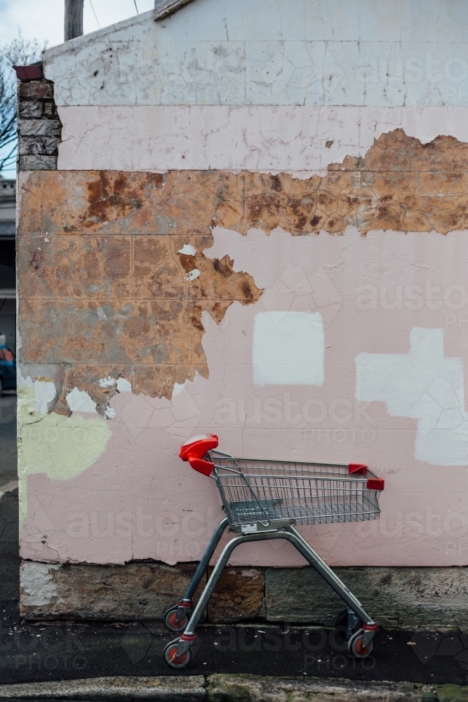Abandoned trolley in front of patchy brick wall - Australian Stock Image