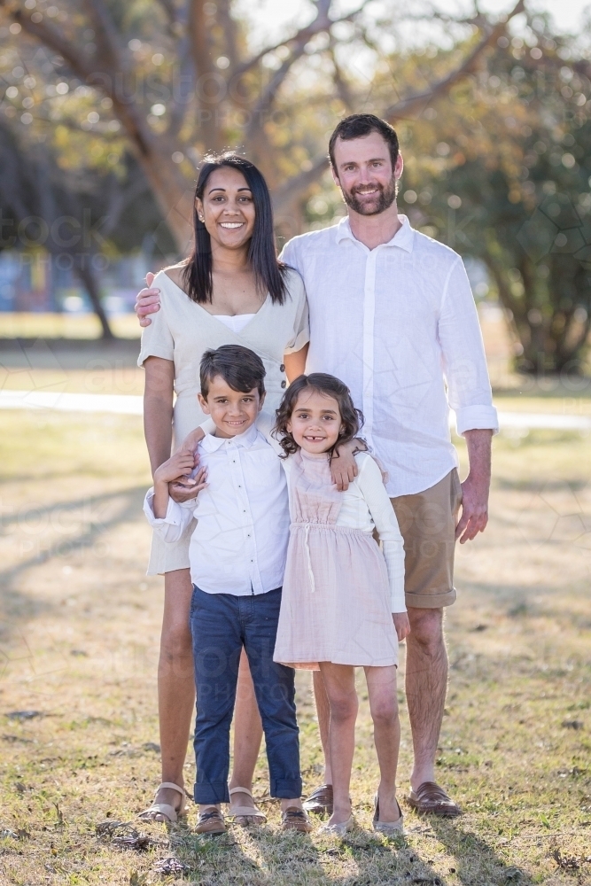 Aboriginal and Caucasian family standing together with twin children - Australian Stock Image