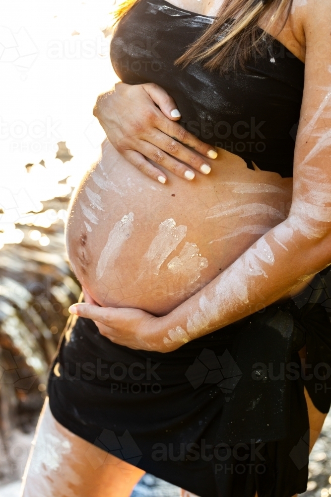 Aboriginal Australian pregnant woman with traditional ochre paint on belly - Australian Stock Image