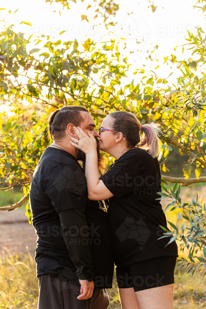 Aboriginal Australian Worimi couple kiss in bushland - Australian Stock Image