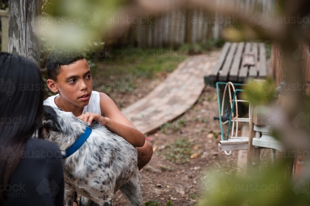 Aboriginal boy and girl with dog in backyard - Australian Stock Image