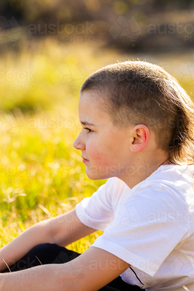 Aboriginal boy in profile sitting alone - Australian Stock Image