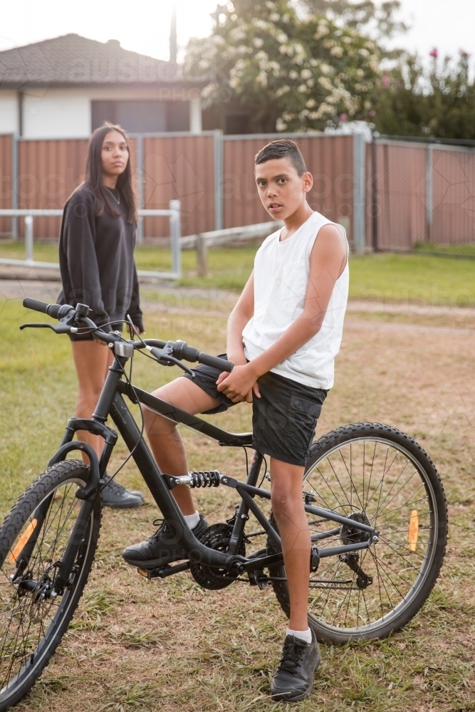 Aboriginal boy riding bike in backyard - Australian Stock Image