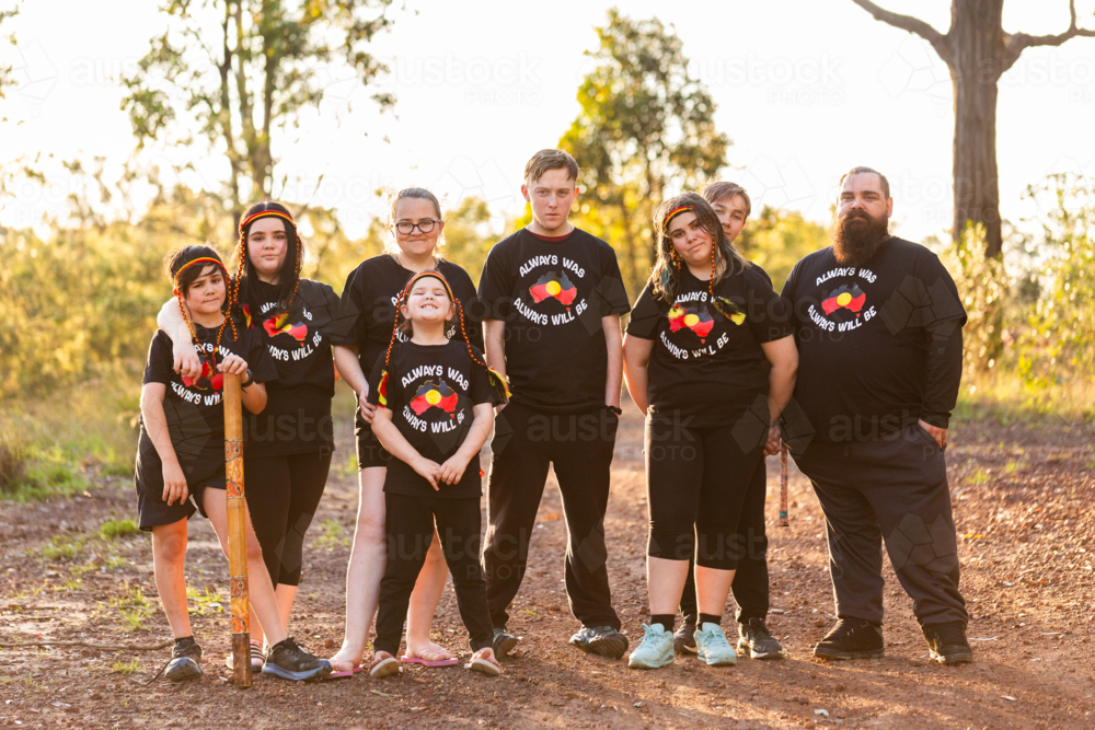 Aboriginal family standing together in golden light in Australian bushland - Australian Stock Image