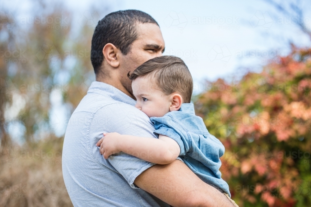 Aboriginal father holding mixed race son in arms - Australian Stock Image