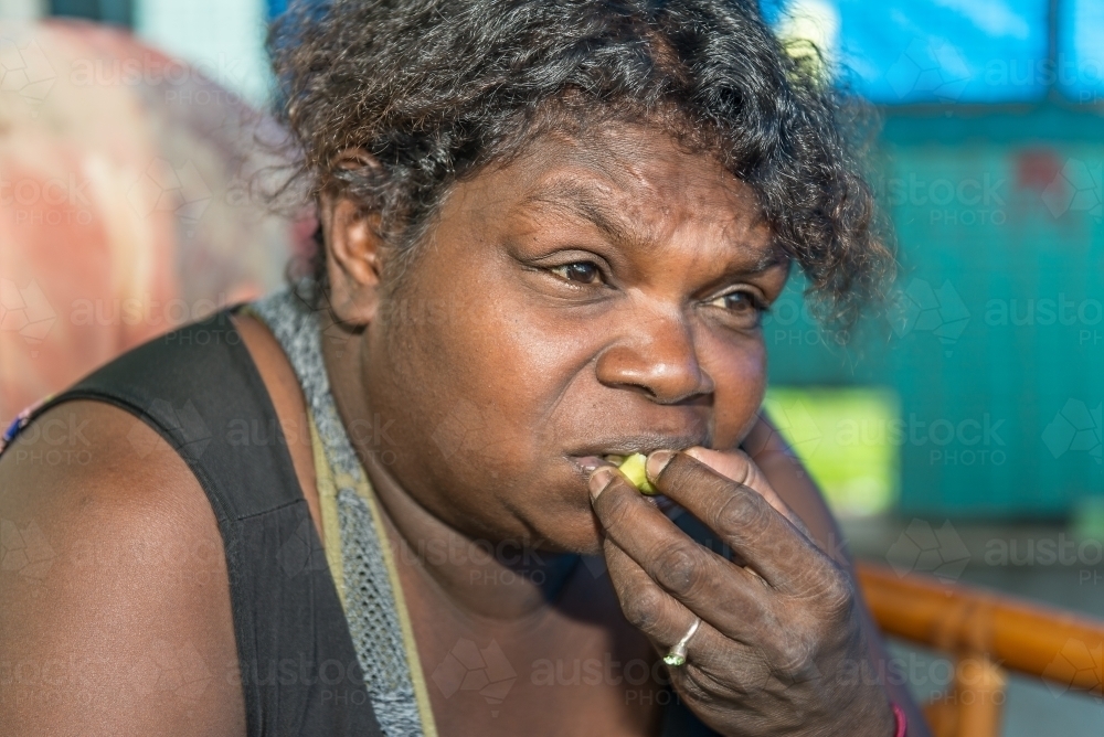 Aboriginal female eating Kakadu Plum - Australian Stock Image