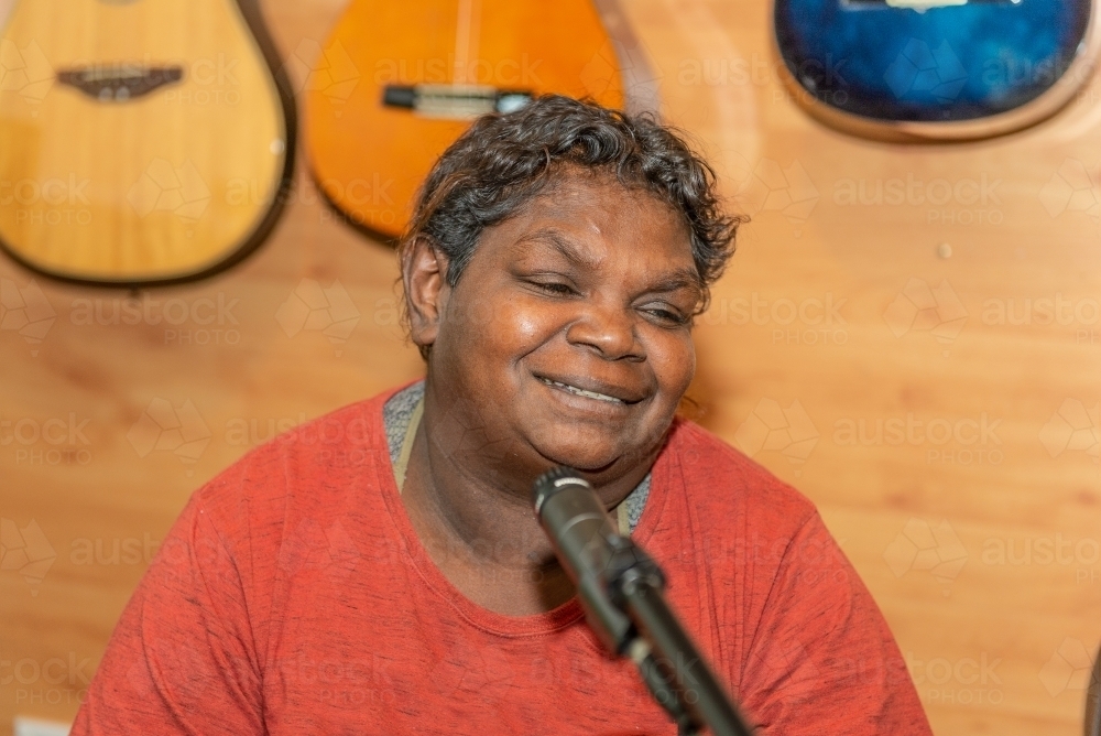Aboriginal lady singing and playing music - Australian Stock Image