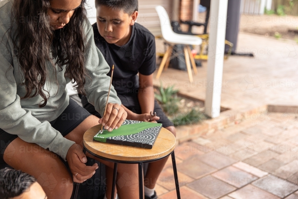 Aboriginal girl and boy dot painting together - Australian Stock Image