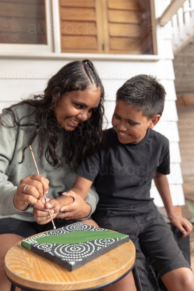 Aboriginal girl and boy dot painting together - Australian Stock Image