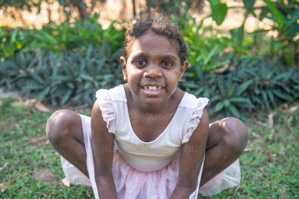 Aboriginal girl crouching in ballet dress - Australian Stock Image