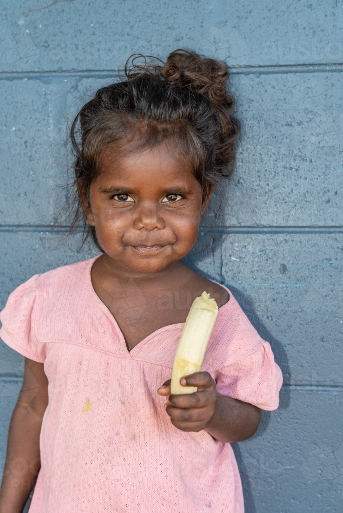 Aboriginal girl eating banana - Australian Stock Image