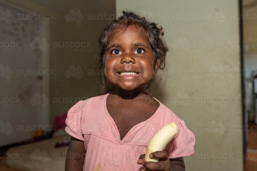 Aboriginal girl eating banana - Australian Stock Image