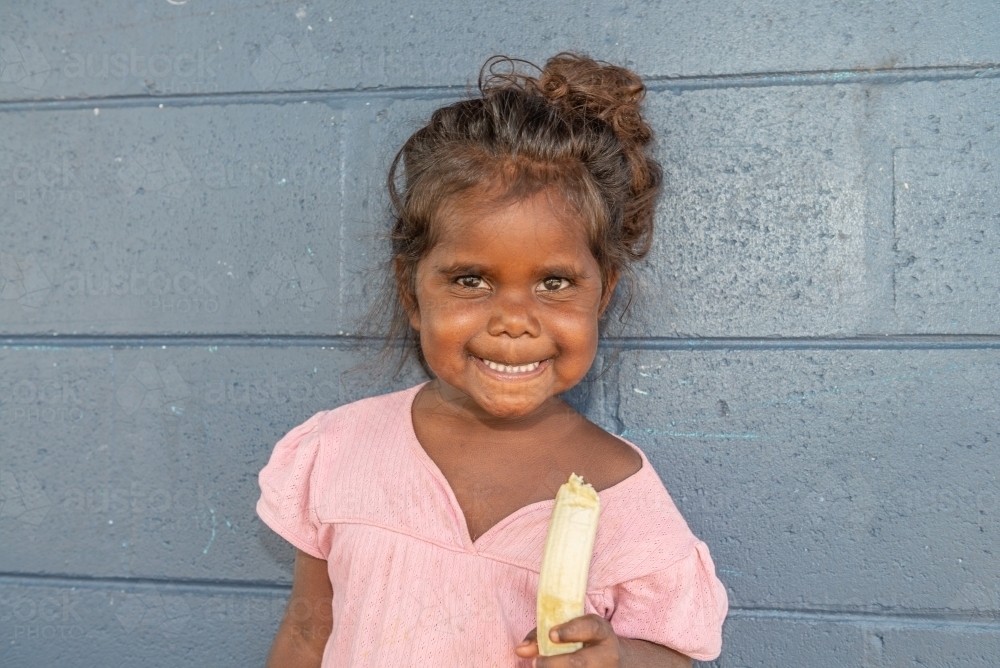 Aboriginal girl eating banana - Australian Stock Image