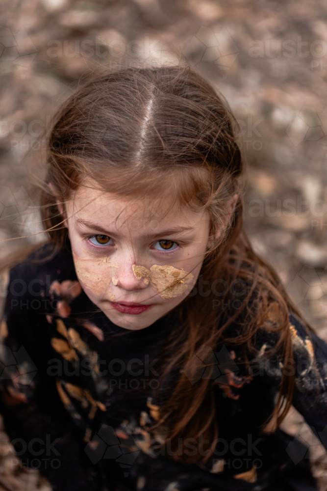 Aboriginal girl looking up wearing traditional ochre paint on face - Australian Stock Image