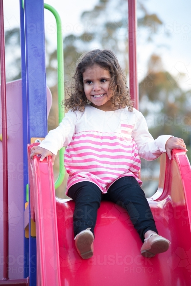 Aboriginal girl on slide at park - Australian Stock Image