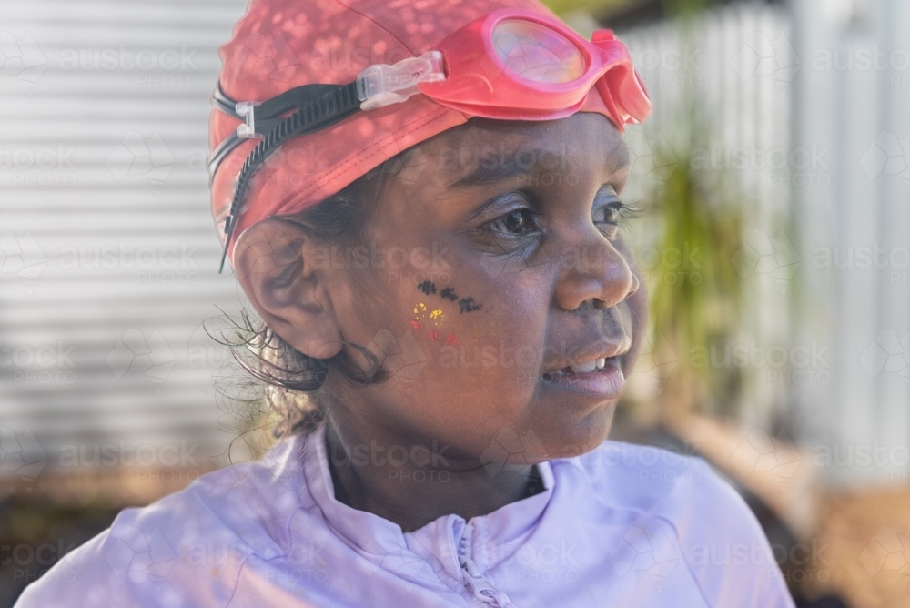 Aboriginal girl with swimming cap, goggles and aboriginal colours on cheek - Australian Stock Image
