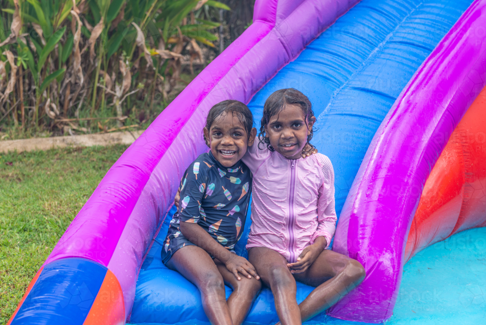 Aboriginal girls on colourful water slide - Australian Stock Image
