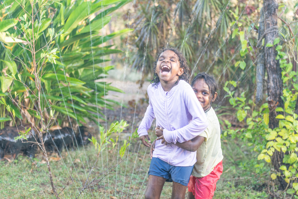 Aboriginal girls playing with sprinkler - Australian Stock Image