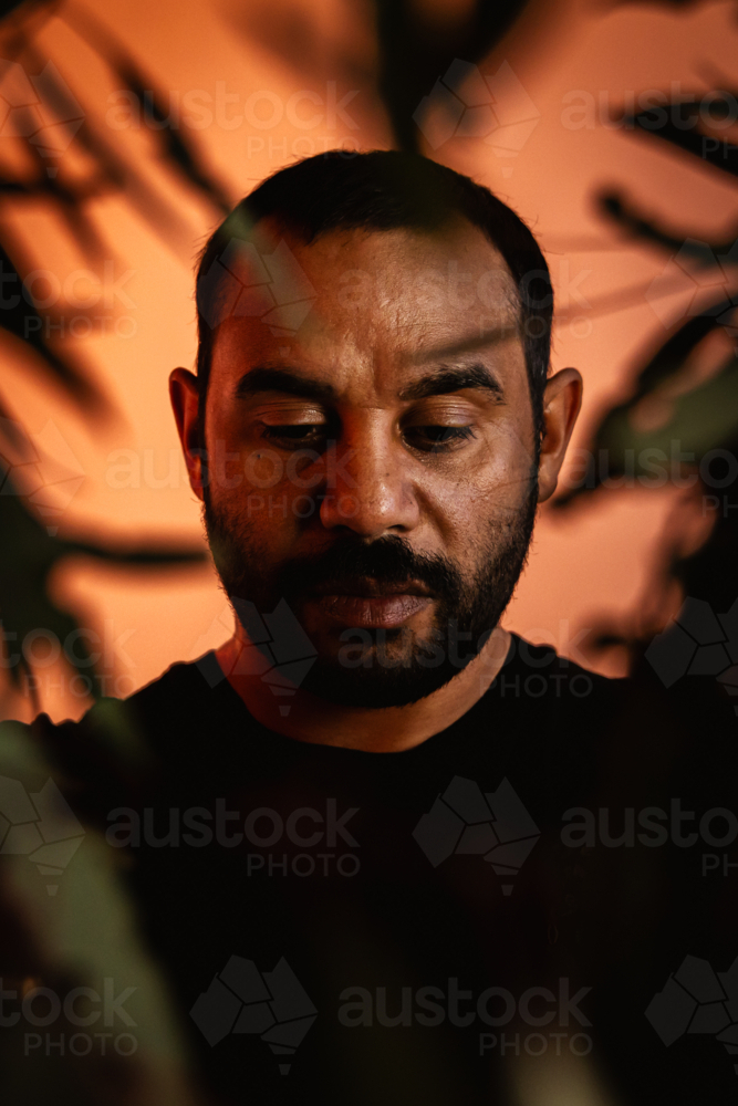 Aboriginal male headshot with leaves In front - Australian Stock Image