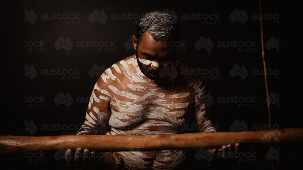 Aboriginal male looking down at didgeridoo - Australian Stock Image