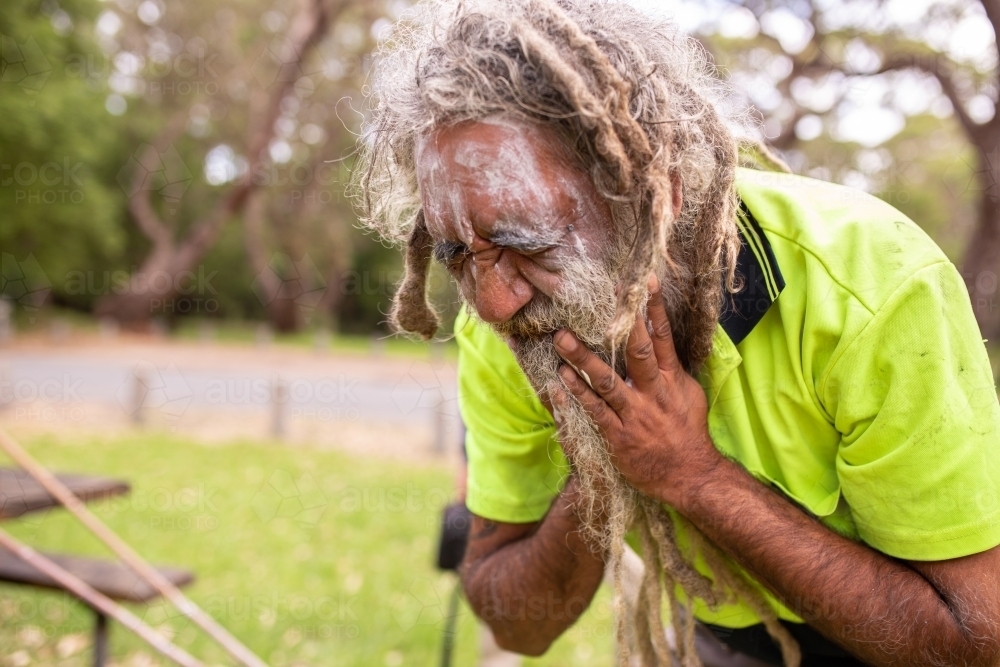Aboriginal man applying white face paint - Australian Stock Image