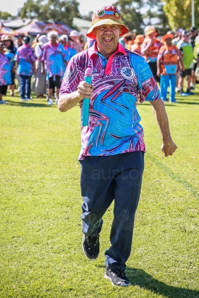 Aboriginal man holding baton in relay race - Australian Stock Image