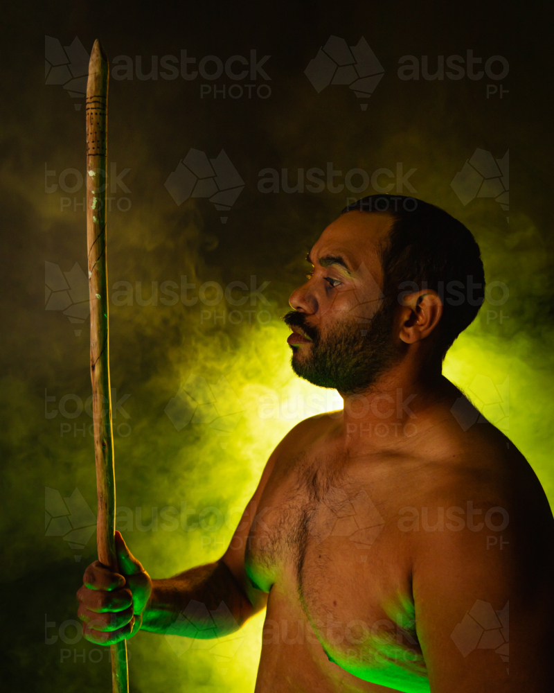 Aboriginal man holding spear looking to the side - Australian Stock Image
