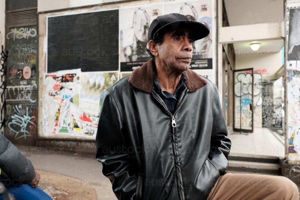 Aboriginal man in leather jacket and hat outside on the street - Australian Stock Image