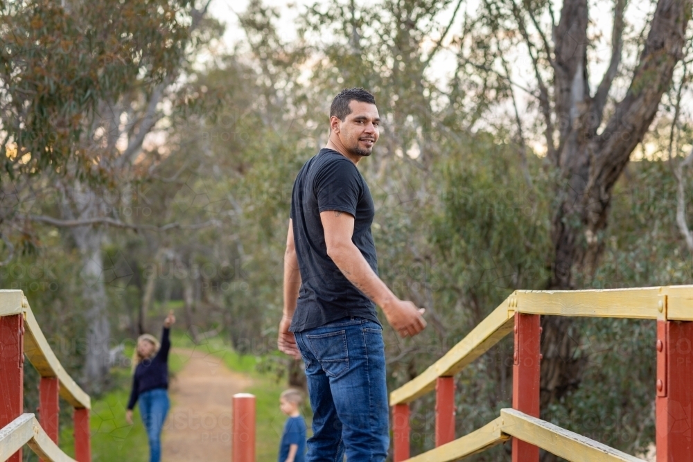aboriginal man looking over his shoulder with children blurred in background - Australian Stock Image